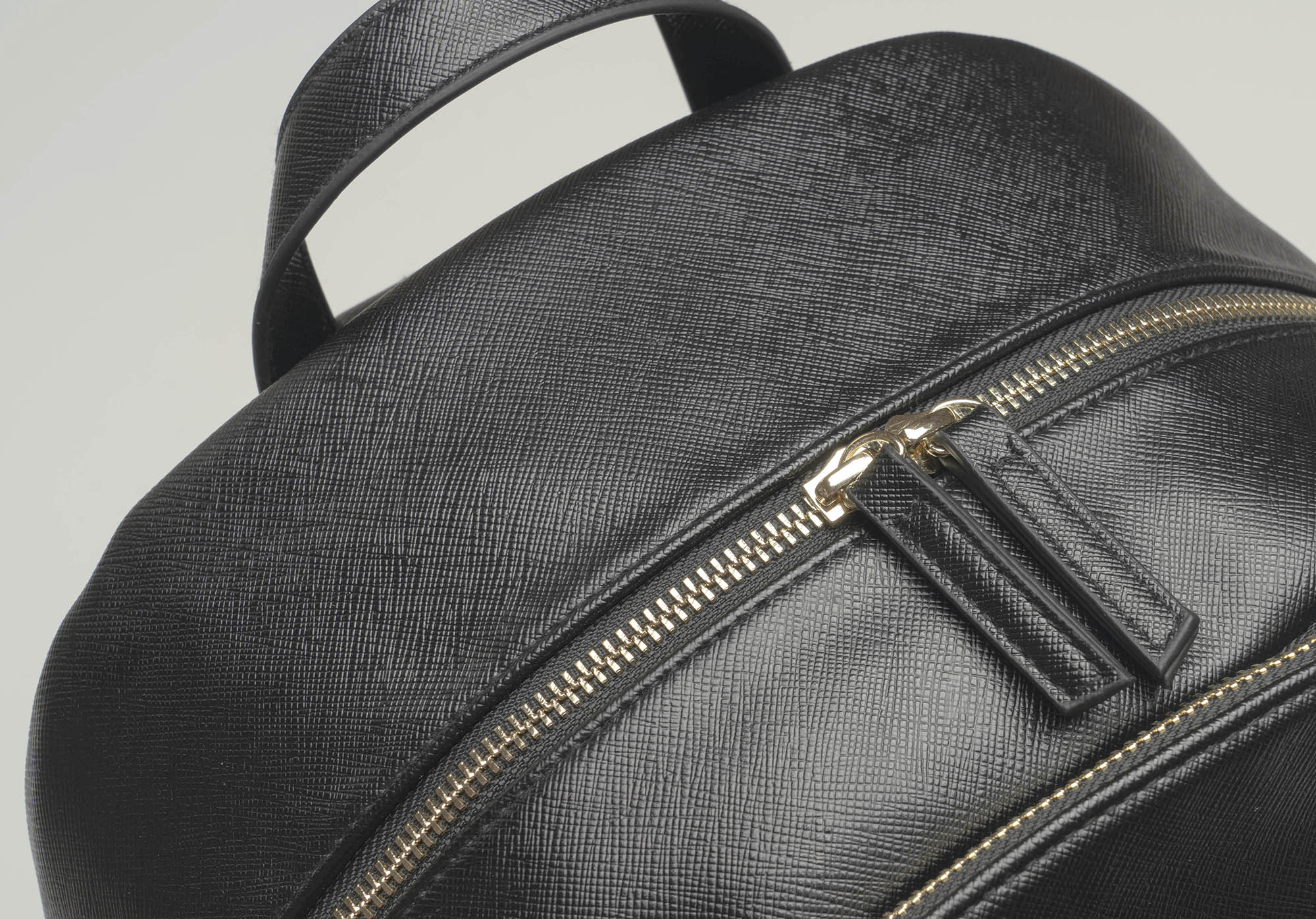 A detailed close-up of the bag's faux leather texture and the metal zipper with double pullers.