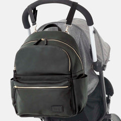 The backpack attached to a stroller, illustrating its compatibility with pushchairs through the use of the included buggy clips